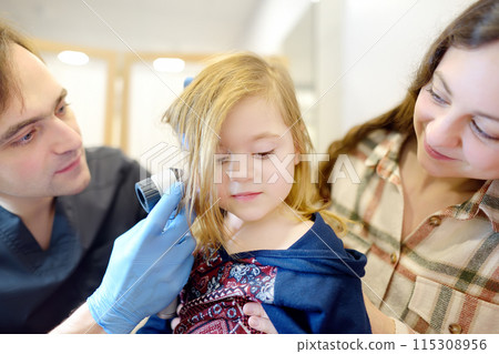 A caring doctor checks moles on the skin of a small child. A dermatologist looks at a rash on the neck of a girl using a dermatoscope. Baby at a pediatrician appointment A caring doctor checks moles on the skin of a small child. A dermatologist looks at a rash on the neck of a girl using a dermatoscope. Baby at a pediatrician appointment 115308956