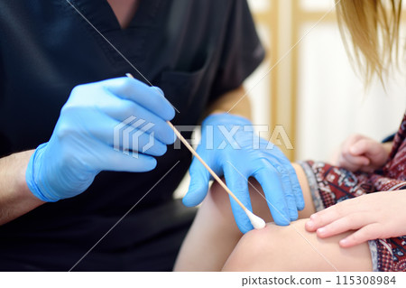 A caring doctor checks moles on the skin of a small child. Dermatologist remove of benign tumors with liquid nitrogen for cute preschooler girl. Baby fears of treat. A caring doctor checks moles on the skin of a small child. Dermatologist remove of benign tumors with liquid nitrogen for cute preschooler girl. Baby fears of treat. 115308984