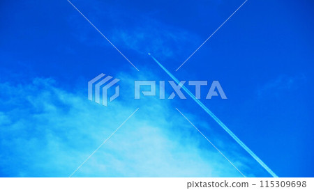 A beautiful scene of a contrail stretching straight into the blue sky 115309698