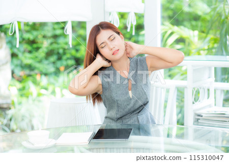 Young asian businesswoman massages neck while sitting at garden office. Young asian businesswoman massages neck while sitting at garden office. 115310047