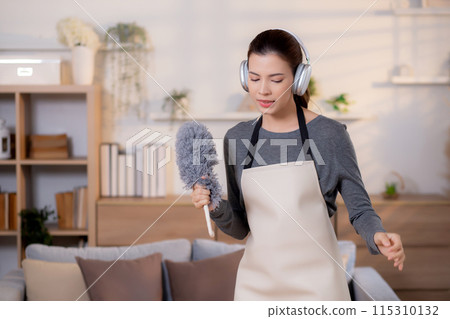 Young asian woman dusting while listening to music with headphones. 115310132