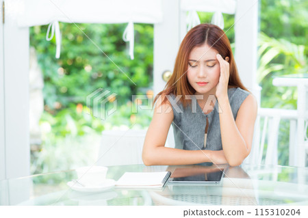 Young asian businesswoman headache with stress while sitting in garden at office. Young asian businesswoman headache with stress while sitting in garden at office. 115310204