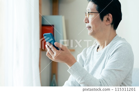 Middle-aged man checking his smartphone Middle-aged man checking his smartphone 115311201