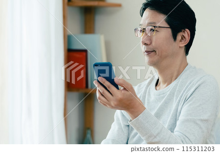 Middle-aged man checking his smartphone Middle-aged man checking his smartphone 115311203