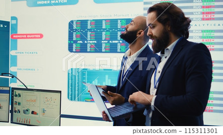 Team of investors analyzing profit amount and making decisions to fund another business project, examine big data on a huge display. Associates verifying efficiency and budget. Camera B. Team of investors analyzing profit amount and making decisions to fund another business project, examine big data on a huge display. Associates verifying efficiency and budget. Camera B. 115311301