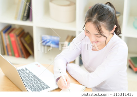 A woman sitting at a table and using a computer A woman sitting at a table and using a computer 115311433