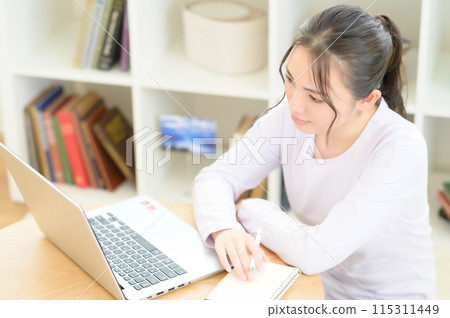 一位女士坐在桌旁操作電腦 一位女士坐在桌旁操作電腦 115311449