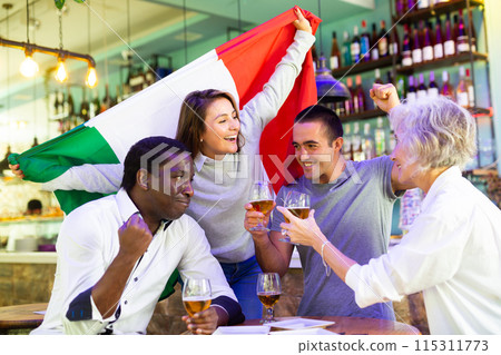 Extremely happy italian man and woman supporters waving national flag, celebrating victory with glasses of beer in pub Extremely happy italian man and woman supporters waving national flag, celebrating victory with glasses of beer in pub 115311773