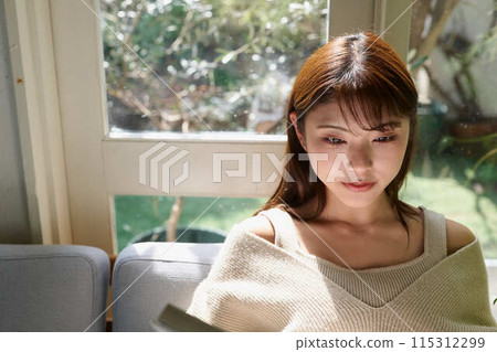 Woman reading by the window Woman reading by the window 115312299