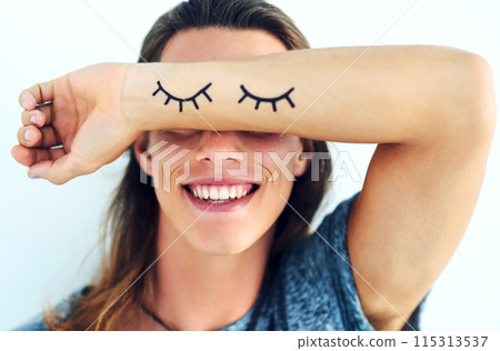 Person, happy and arm covering eyes with shy, eyelash and emoji isolated on white background. Playful, smile and joyful with hiding face, funny or embarrassed gesture with laugh expression in studio. 115313537