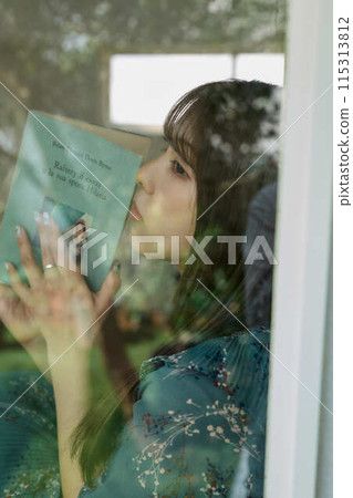 A woman reading a book at the window side 115313812