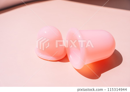 Pink silicone vacuum cups for massage on a pink background Pink silicone vacuum cups for massage on a pink background 115314944