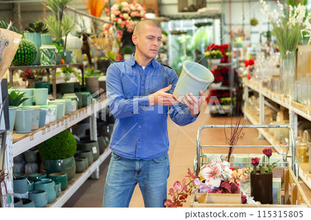 Positive man carefully choosing flower pots in a flower shop 115315805