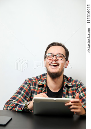 Young man using a tablet with a happy smile. Modern young man with tablet and happy expression. Vertical, white background. Handsome young man using a digital tablet 115316035
