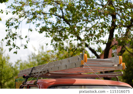 Multi Segment Ladder Carrier at Car Roof Top Rack. car with roof ladder, transporting equipment, vehicle carrying load. Blurred nature background 115316075