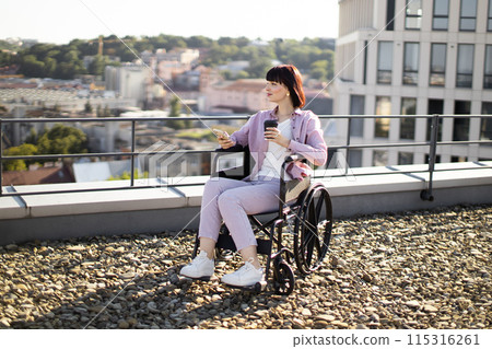 Woman in wheelchair enjoying coffee and using smartphone outdoors Woman in wheelchair enjoying coffee and using smartphone outdoors 115316261