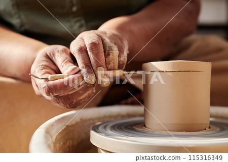 Close up of female hands shaping clay on pottery wheel in sunlight creating artisanal ceramics copy space 115316349