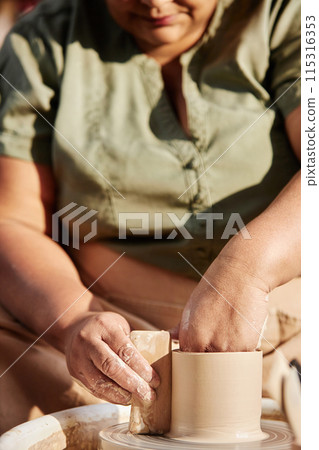 Vertical closeup of senior African American woman enjoying pottery class in sunlight Vertical closeup of senior African American woman enjoying pottery class in sunlight 115316353