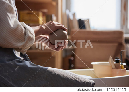 Side view closeup of unrecognizable adult woman gently holding clay ball in hands and enjoying ceramics class copy space Side view closeup of unrecognizable adult woman gently holding clay ball in hands and enjoying ceramics class copy space 115316425