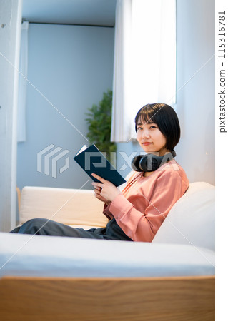 一位女士一邊聽音樂一邊閱讀/重新學習技能 115316781