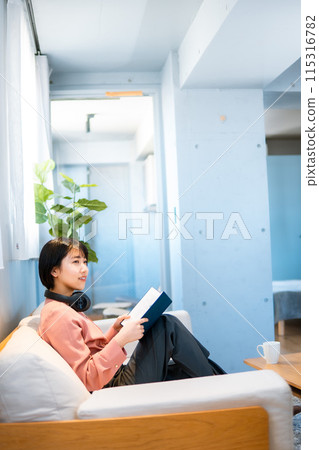 一位女士一邊聽音樂一邊閱讀/重新學習技能 115316782