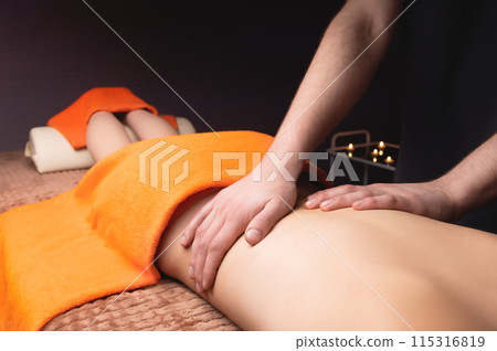 High angle view of a massage therapist massaging the back of a young client on a massage table. Woman taking care procedure in salon 115316819