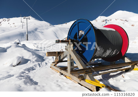 Power cable on reels. Thick electrical wire. Wire spools for outdoor use. Electrical products at a ski resort en street in the snow Power cable on reels. Thick electrical wire. Wire spools for outdoor use. Electrical products at a ski resort en street in the snow 115316820