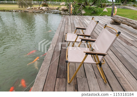 Chairs on wood pergola by carp fish pond in spring garden 115318184