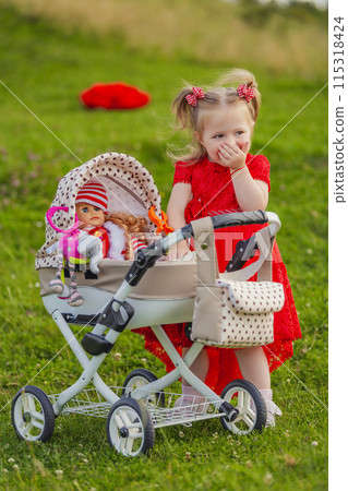 little girl plays with a doll and a stroller 115318424