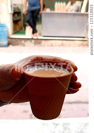 Hot milk tea or chai in traditional kulhad or clay pot or earthen cup held by hand Hot milk tea or chai in traditional kulhad or clay pot or earthen cup held by hand 115318925