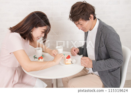 A friendly couple in a coffee shop at a table with cake A friendly couple in a coffee shop at a table with cake 115319624