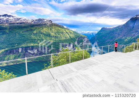Tourist looking at Geirangerfjord from Flydasjuvet viewpoint Norway Tourist looking at Geirangerfjord from Flydasjuvet viewpoint Norway 115320720
