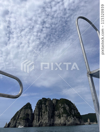 A ladder of a boat in front of huge rock formations on the sea A ladder of a boat in front of huge rock formations on the sea 115320939
