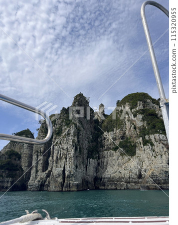 A ladder of a boat in front of huge rock formations on the sea A ladder of a boat in front of huge rock formations on the sea 115320955