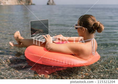 A woman is sitting on a pink inflatable raft in the water, using a laptop. Concept of relaxation and leisure, as the woman is enjoying her time by the water while working on her laptop. A woman is sitting on a pink inflatable raft in the water, using a laptop. Concept of relaxation and leisure, as the woman is enjoying her time by the water while working on her laptop. 115321204