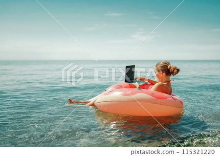 Woman laptop sea. Freelancer woman in sunglases floating on an inflatable big pink donut with a laptop in the sea. People summer vacation rest lifestyle concept 115321220