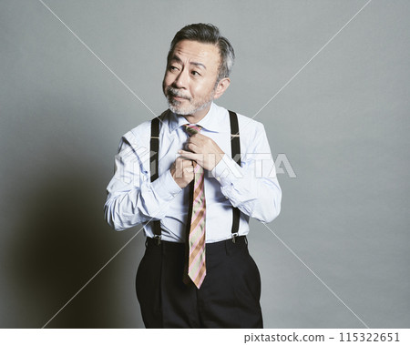 A middle-aged businessman wearing a suit on a gray background 115322651