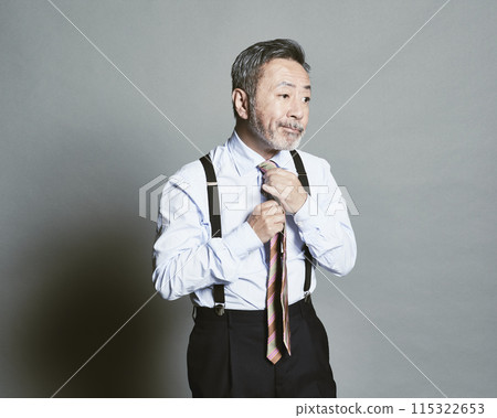 A middle-aged businessman wearing a suit on a gray background 115322653