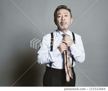 A middle-aged businessman wearing a suit on a gray background 115322664