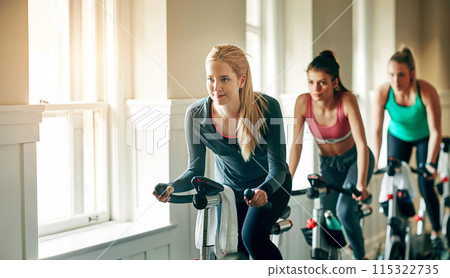 People, exercise bike and gym for cardio, training and cycling for fitness or spin class. Women, riding and stationary machine for workout challenge, aerobic instructor and equipment for practice 115322735
