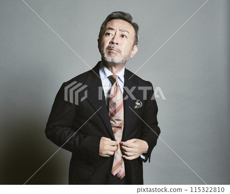 A middle-aged businessman wearing a suit on a gray background A middle-aged businessman wearing a suit on a gray background 115322810