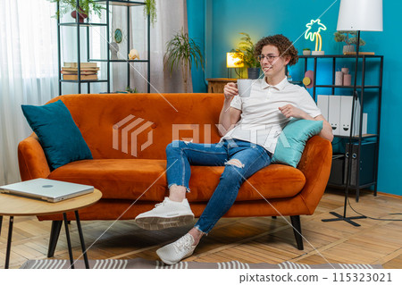 Happy young man smelling enjoy drinking cup of beverage hot coffee taking a break relaxing at home 115323021