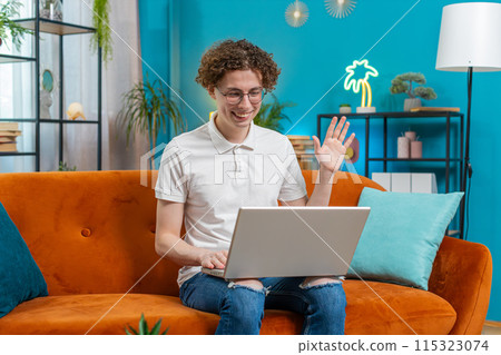 Young man freelancer with laptop making video webcam conference call with colleagues, waving hello 115323074