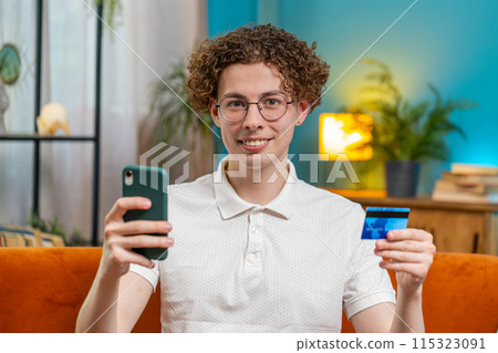 Man using credit bank card and smartphone while transferring money purchases online shopping at home 115323091