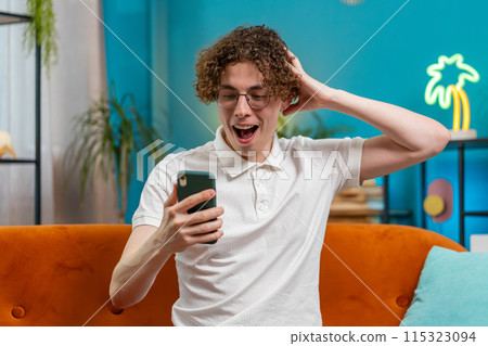 Surprised excited man winner holding smartphone reading good news amazed by online game casino win 115323094