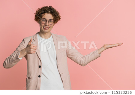 Young man showing thumbs up and pointing at right on blank space place for your advertisement logo Young man showing thumbs up and pointing at right on blank space place for your advertisement logo 115323236