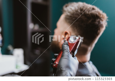 A man is getting his hair cut by a barber A man is getting his hair cut by a barber 115323303