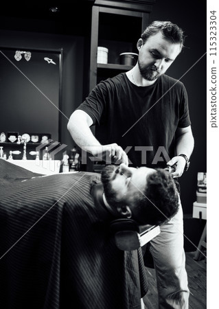 A man is getting his hair cut by another man 115323304