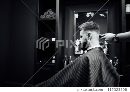 A man is getting his hair cut by a barber 115323306