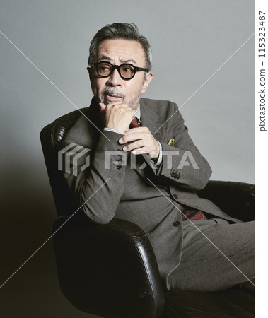 A middle-aged businessman wearing a suit on a gray background 115323487